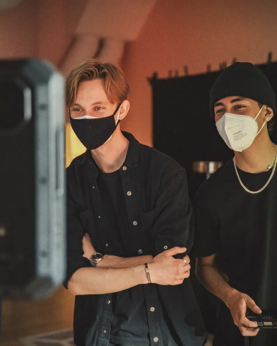 Two crew members in face masks watching a monitor on set