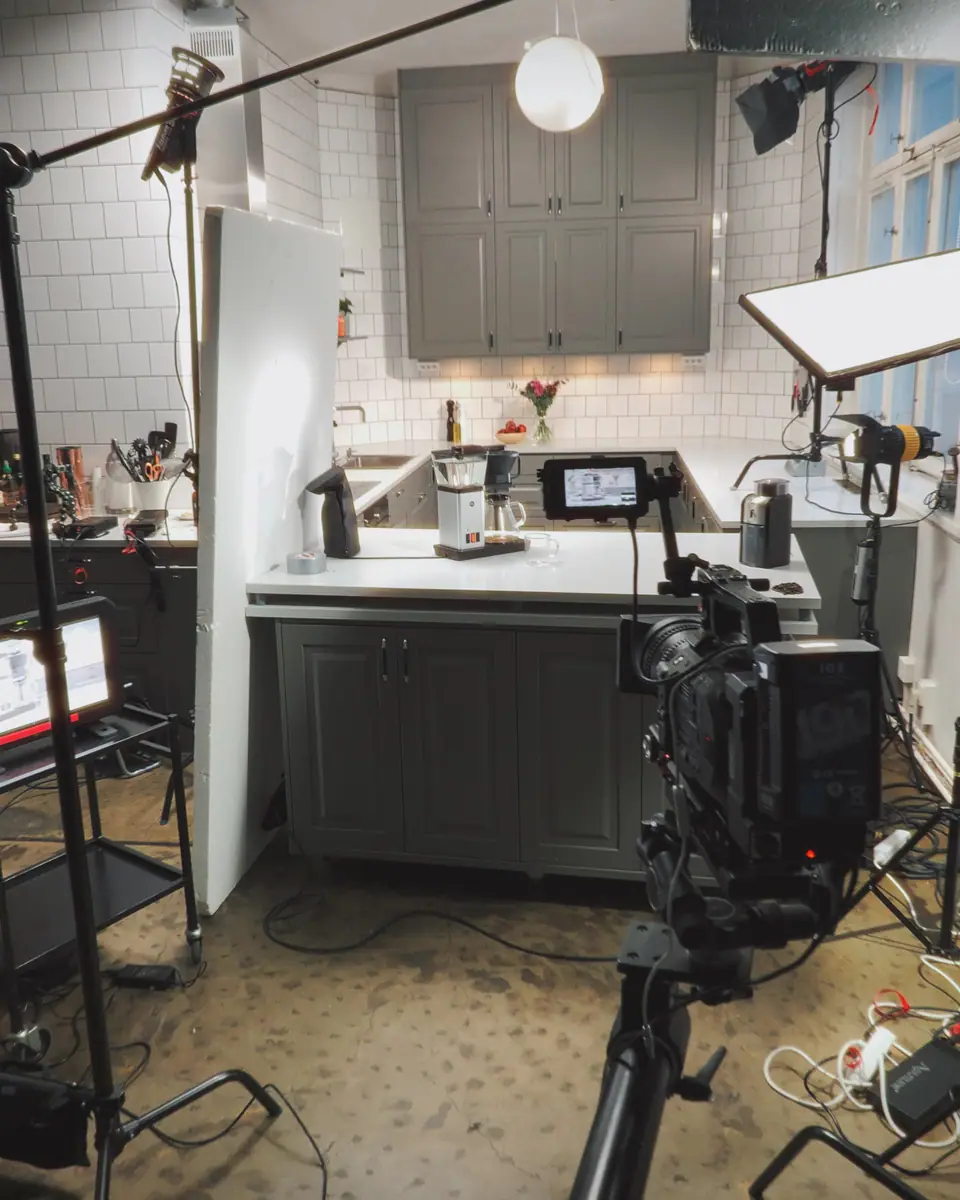 A cinema camera and lights set up in front of a grey studio kitchen