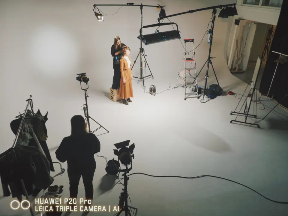 A white cyclorama studio with lights and a couple posing, crew in the foreground