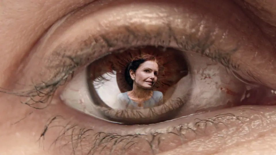 Extreme close-up of an eye with a woman's face reflected in the iris