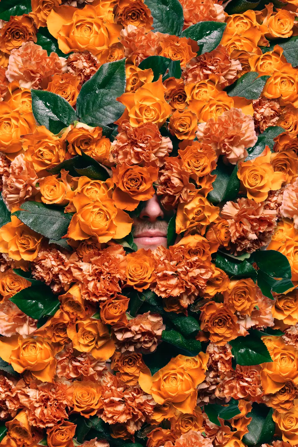 A face almost hidden in a wall of orange roses and carnations