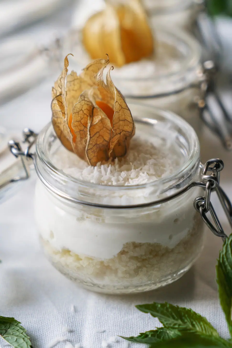 A creamy dessert in a glass jar topped with a physalis