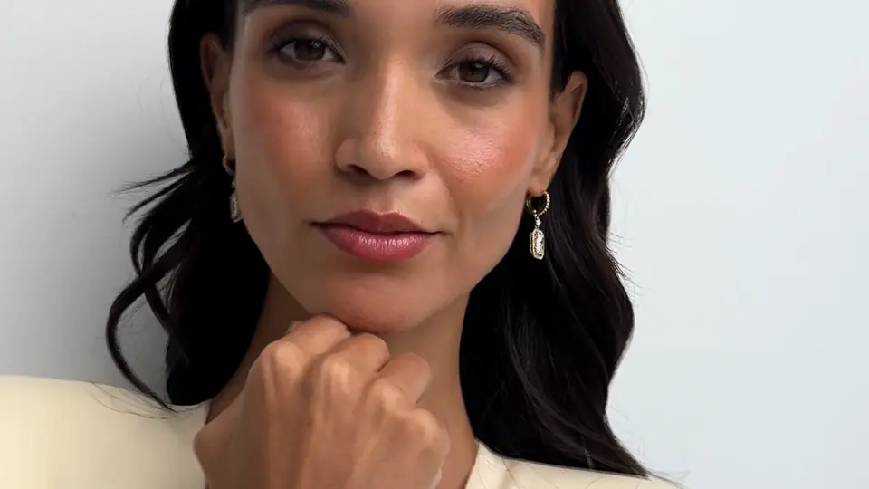 Widescreen film: close-ups of drop earrings and a gold cuff on a model in cream