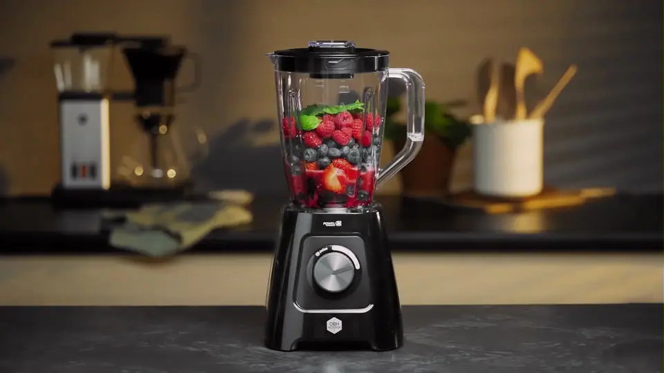 An OBH Nordica blender filled with berries on a dark kitchen counter
