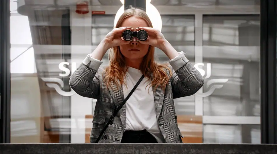 A woman looking through binoculars at a train station