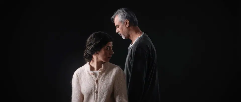 A man and a woman standing close together against a black background
