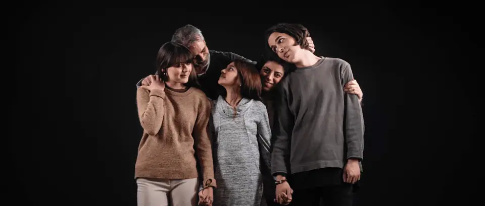 Four people leaning into each other against a black background
