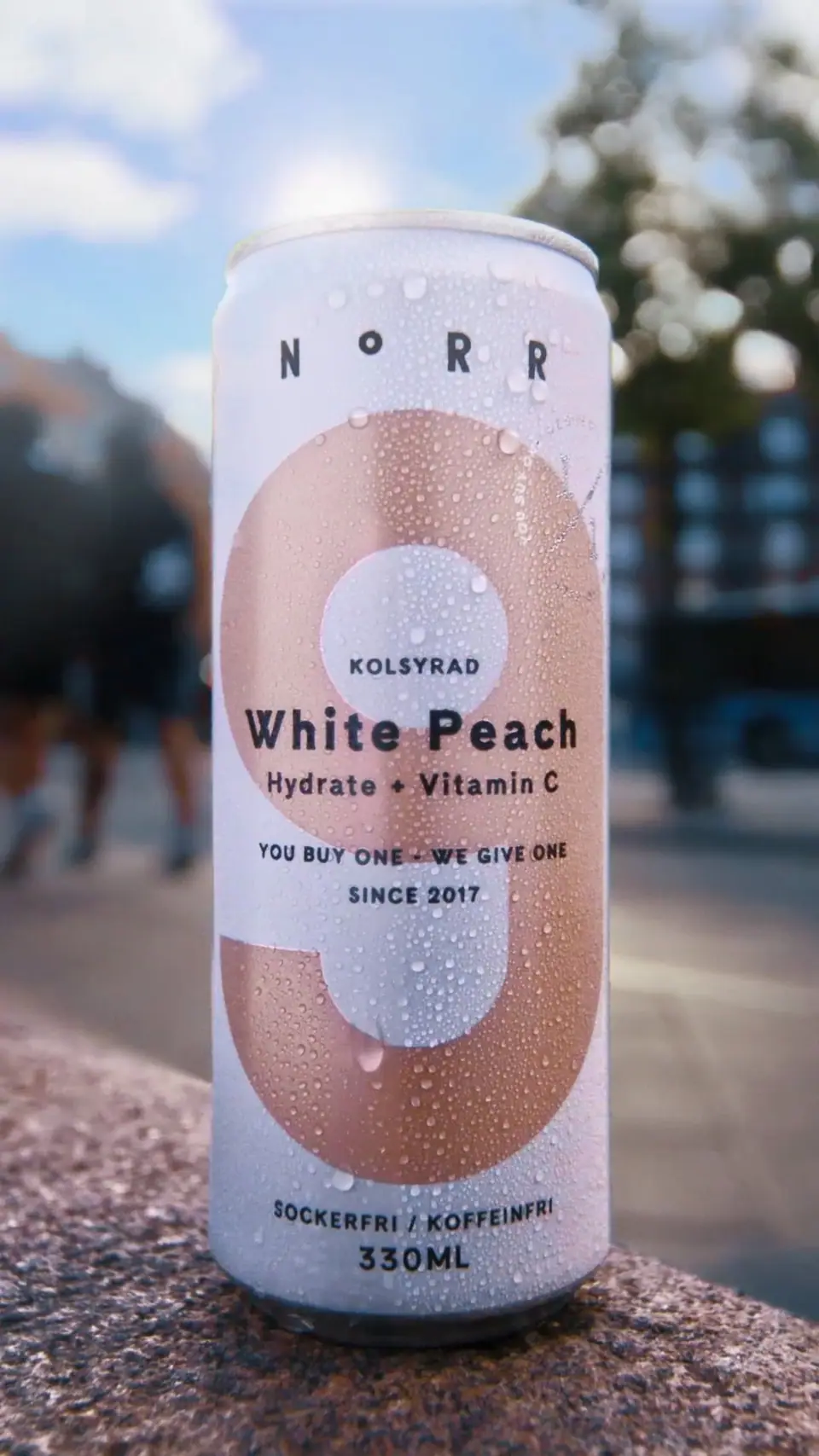 A can of Norr White Peach on a stone ledge above a city street