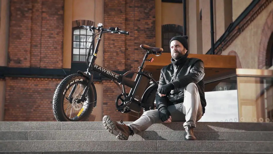 A man sitting on brick steps beside an electric fat-tire bike