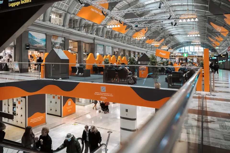 Wave-shaped orange campaign graphics running through the station hall
