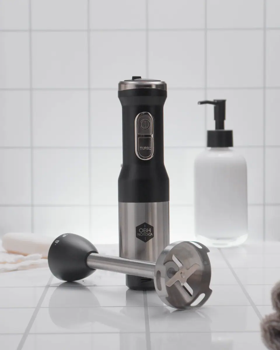 An OBH Nordica hand blender and its attachments on white tiles