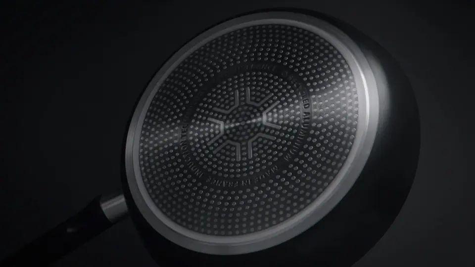 Macro of a frying pan's textured surface, lit low against black