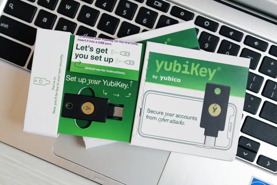 Open YubiKey box: the key in its tray with arrows showing where it goes, a 'Let's get you set up' fold-out, and the box front showing the key plugged into a phone outline