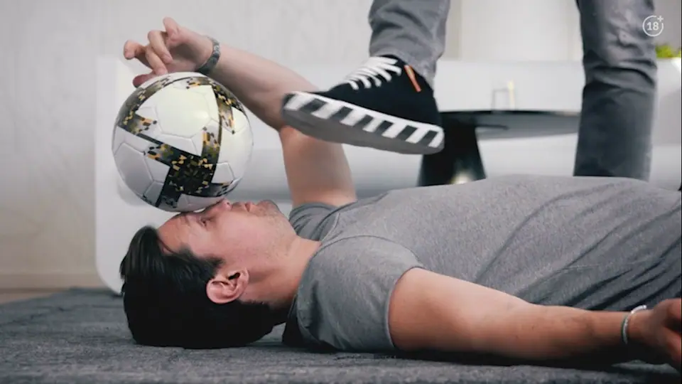 Zlatan kicks a football off the head of a man lying on the floor